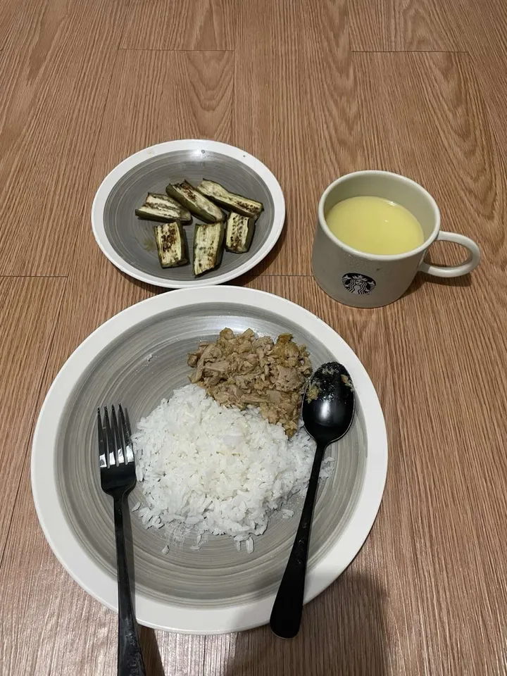 A dinner of white rice and tuna on a grey plate, a side plate of grilled eggplant slices, and a mug of corn soup, on a wood-grain surface.